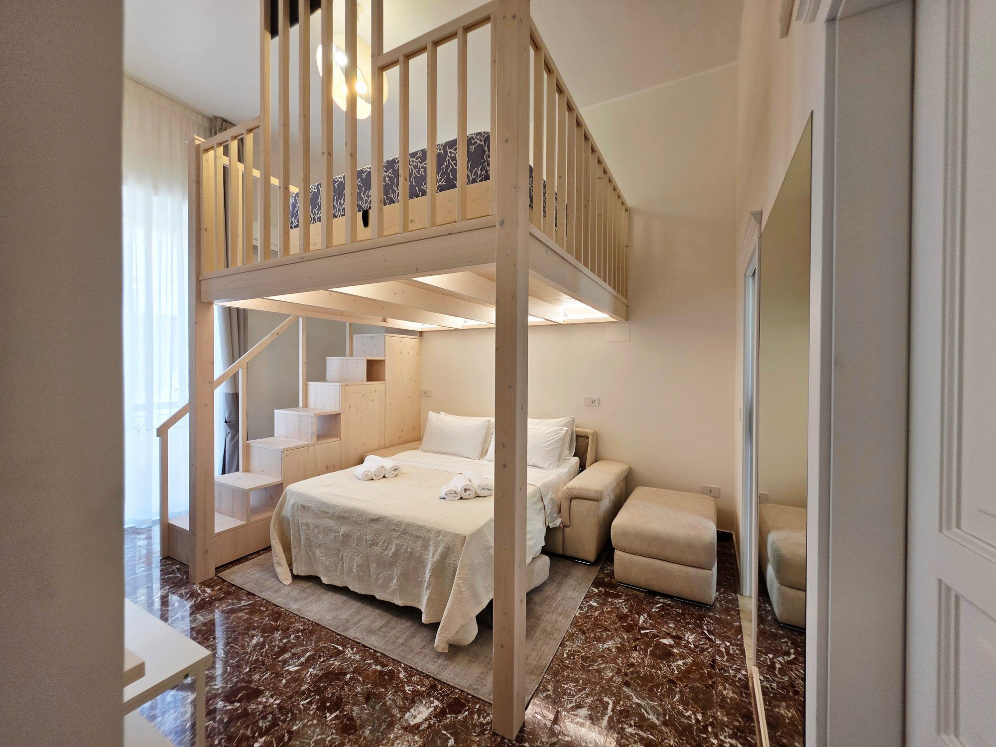 Soppalco con il letto king e, sotto, il salotto con il divano letto